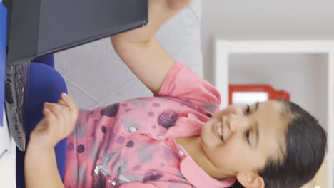 Vertical-video-of-Successful-girl-child-sees-good-results-on-laptop.